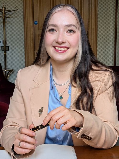 Mirella at a desk with a notebook and pen, smiling